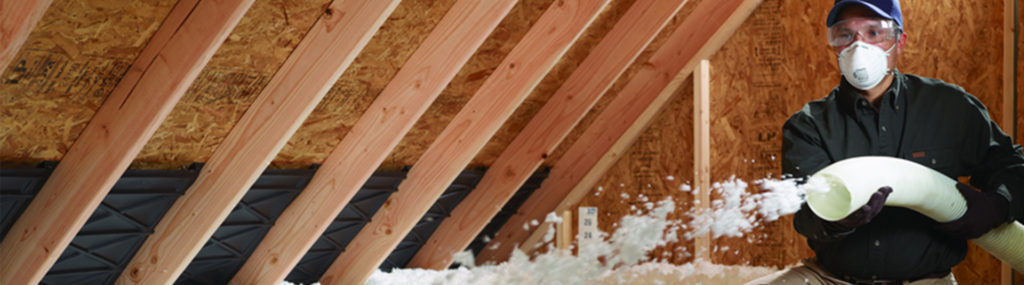 Insulation being blown into an attic by a technician